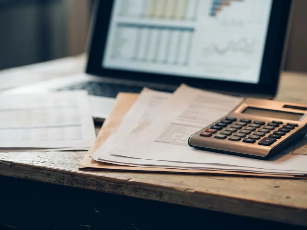 Financial documents, a calculator and a laptop with charts on an organized desk