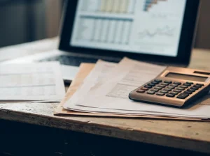 Financial documents, a calculator and a laptop with charts on an organized desk
